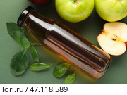 Стеклянная бутылка свежего яблочного уксуса и фруктов на зеленом фоне. Стоковое фото, фотограф Pixel_shot / Фотобанк Лори