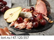 Шиферная тарелка с ассортиментом вкусных мясных деликатесов на сером фоне. Стоковое фото, фотограф Pixel_shot / Фотобанк Лори