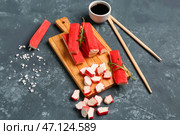Деревянная доска с вкусными крабовыми палочками на зеленом фоне. Стоковое фото, фотограф Pixel_shot / Фотобанк Лори
