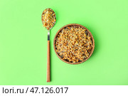 Чашка и ложка с пророщенной пшеницей на светло-зеленом фоне. Стоковое фото, фотограф Pixel_shot / Фотобанк Лори