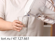Женщина наливает чистую воду из фильтрующего кувшина в стакан. Стоковое фото, фотограф Pixel_shot / Фотобанк Лори