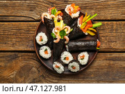 Тарелка с вкусными конусами и роллами суши на деревянном фоне. Стоковое фото, фотограф Pixel_shot / Фотобанк Лори