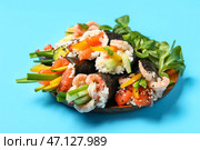 Тарелка с вкусными конусами суши и салатом ламбс-леттус на цветном фоне. Стоковое фото, фотограф Pixel_shot / Фотобанк Лори