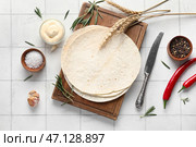 Деревянная доска с свежим лавашем, специями и соусом на белом плиточном фоне. Стоковое фото, фотограф Pixel_shot / Фотобанк Лори