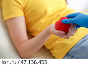 Женщина-донор крови берет грип-мяч у медсестры в клинике, крупным планом. Стоковое фото, фотограф Pixel_shot / Фотобанк Лори