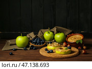Пробковый коврик из вкусных яблочных кружков с ореховым маслом, черникой и фундуком на деревянном столе. Стоковое фото, фотограф Pixel_shot / Фотобанк Лори