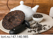 Сухой прессованный чай пуэр, нож и чайник на деревянном фоне, крупным планом. Стоковое фото, фотограф Pixel_shot / Фотобанк Лори