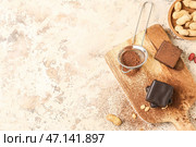Деревянная доска с вкусными конфетами из птичьего молока и какао-порошком на светлом фоне. Стоковое фото, фотограф Pixel_shot / Фотобанк Лори
