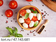 Деревянная миска с вкусным сыром моцарелла, помидорами и специями на светлом фоне. Стоковое фото, фотограф Pixel_shot / Фотобанк Лори