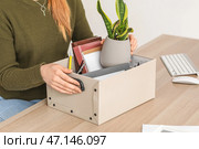 Уволенная молодая женщина с упакованными вещами сидит за столом в офисе, крупным планом. Стоковое фото, фотограф Pixel_shot / Фотобанк Лори