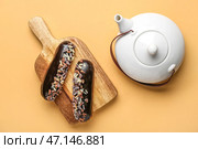 Деревянная доска с вкусными эклерами и чайником на цветном фоне. Стоковое фото, фотограф Pixel_shot / Фотобанк Лори