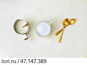 Стеклянная чашка угольного латте, кувшин с молоком и ложки на светлом столе. Стоковое фото, фотограф Pixel_shot / Фотобанк Лори