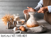 Женщина просеивает муку на кухне. Стоковое фото, фотограф Pixel_shot / Фотобанк Лори