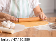 Зрелая женщина раскатывает тесто для печенья за столом на кухне. Стоковое фото, фотограф Pixel_shot / Фотобанк Лори