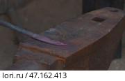 A blacksmith makes a metal blade on an anvil using hammer blows. Стоковое видео, видеограф Алексей Сергеев / Фотобанк Лори