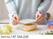 Женщина закрывает пластиковый контейнер с кукурузой на кухне, крупным планом. Стоковое фото, фотограф Pixel_shot / Фотобанк Лори