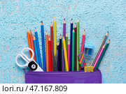 Чемодан с карандашами, ножницами, ластиком и точилкой на цветном фоне, крупным планом. Стоковое фото, фотограф Pixel_shot / Фотобанк Лори