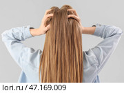 Молодая женщина страдает от громкого шума на сером фоне, вид сзади. Стоковое фото, фотограф Pixel_shot / Фотобанк Лори