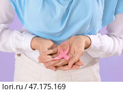 Молодая мусульманка с розовой лентой на лиловом фоне, крупным планом. Концепция осведомленности о раке груди. Стоковое фото, фотограф Pixel_shot / Фотобанк Лори