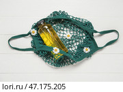 Сетчатый мешок с бутылкой сока и красивыми цветами ромашки на светлом деревянном фоне. Стоковое фото, фотограф Pixel_shot / Фотобанк Лори
