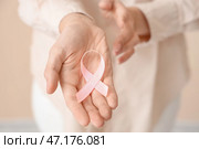 Молодая женщина с розовой лентой на бежевом фоне, крупным планом. Концепция осведомленности о раке груди. Стоковое фото, фотограф Pixel_shot / Фотобанк Лори