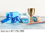 Композиция к Хануке с суфганиями, кубком, подарочными коробками и крутильцами на голубом гранж столе, крупным планом. Стоковое фото, фотограф Pixel_shot / Фотобанк Лори