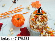 Банка с вкусным попкорном, карамельным кукурузным хлопьями и кренделями на белом фоне, крупным планом. Празднование Хэллоуина. Стоковое фото, фотограф Pixel_shot / Фотобанк Лори
