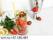 Стол с бокалом свежего клубничного мохито, мерной ложкой и шейкером на белой плитке. Стоковое фото, фотограф Pixel_shot / Фотобанк Лори