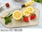 Доска с спелой клубникой, ломтями лимона и мятой на светлом фоне, крупным планом. Стоковое фото, фотограф Pixel_shot / Фотобанк Лори