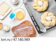 Противень с неприготовленным итальянским пасхальным хлебом и ингредиентами на белом деревянном фоне. Стоковое фото, фотограф Pixel_shot / Фотобанк Лори