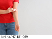 Женщина-донор крови накладывает марлевую повязку на руку на светлом фоне, крупным планом. Стоковое фото, фотограф Pixel_shot / Фотобанк Лори