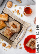 Лоток с вкусным баклавой и стакан турецкого чая на светлом фоне. Стоковое фото, фотограф Pixel_shot / Фотобанк Лори