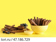 Миски с вкусными шоколадными вафельными трубочками и сгущенным молоком на желтом фоне. Стоковое фото, фотограф Pixel_shot / Фотобанк Лори