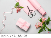 Композиция с подарочной коробкой, оберточной бумагой, ножницами и цветами альстромерии на светлом фоне. Празднование женского дня. Стоковое фото, фотограф Pixel_shot / Фотобанк Лори