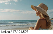A woman on vacation, sitting in a swimsuit and a wide-brimmed straw hat on the beach on a sunny day and looking at the sea. Стоковое AI-изображение, AI-художник Photojuli / Фотобанк Лори