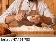 Мужчина-пекарь разбивает яйцо для теста за столом на кухне, крупным планом. Стоковое фото, фотограф Pixel_shot / Фотобанк Лори