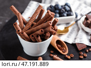 Чаша с вкусными вафельными трубочками на черной деревянной доске. Стоковое фото, фотограф Pixel_shot / Фотобанк Лори