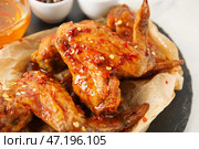 Вкусные жареные куриные крылышки и горячий мед на столе, крупным планом. Стоковое фото, фотограф Pixel_shot / Фотобанк Лори
