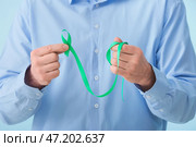 Человек с зеленой лентой, крупным планом. Концепция митохондриальных заболеваний и рака почки. Стоковое фото, фотограф Pixel_shot / Фотобанк Лори