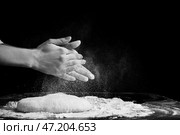 Женщина хлопает в ладоши и посыпает тесто мукой на темном фоне. Стоковое фото, фотограф Pixel_shot / Фотобанк Лори