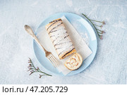 Синяя тарелка с вкусным бисквитом, вилкой и цветочным декором на белом столе. Стоковое фото, фотограф Pixel_shot / Фотобанк Лори