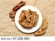 Тарелка с вкусным печеньем бискотти, миндальными орехами, корицей и шоколадом на бежевой бумаге. Стоковое фото, фотограф Pixel_shot / Фотобанк Лори