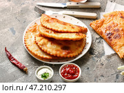Тарелка с чебуреками, соусами, перцем чили и столовыми приборами на фоне гранж. Стоковое фото, фотограф Pixel_shot / Фотобанк Лори