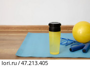 Спортивная бутылка для воды со скакалкой и мячом на коврике у стены со светом. Стоковое фото, фотограф Pixel_shot / Фотобанк Лори