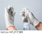 Женщина дезинфицирует ключи от дома на сером фоне. Стоковое фото, фотограф Pixel_shot / Фотобанк Лори