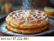 Golden waffles stacked and generously sprinkled with powdered sugar. A piece of butter melts on top, and viscous honey flows down the edges, creating an appetizing shine. The background is slightly blurred, with warm shades that create a cozy atmosphere. The dessert looks especially delicious and is perfect for breakfast or a sweet treat. Стоковое AI-изображение, AI-художник Анна Кривицкая / Фотобанк Лори