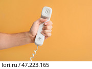 Мужская рука с проводным телефоном на цветном фоне. Стоковое фото, фотограф Pixel_shot / Фотобанк Лори