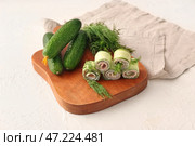 Доска с вкусными рулетиками из огурцов на белом фоне. Стоковое фото, фотограф Pixel_shot / Фотобанк Лори