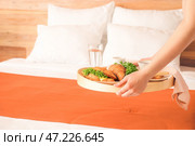 Горничная кладет вкусный завтрак на кровать в гостиничном номере. Стоковое фото, фотограф Pixel_shot / Фотобанк Лори