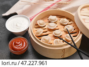 Пароварка с вкусными варениками и соусами на темном фоне. Стоковое фото, фотограф Pixel_shot / Фотобанк Лори